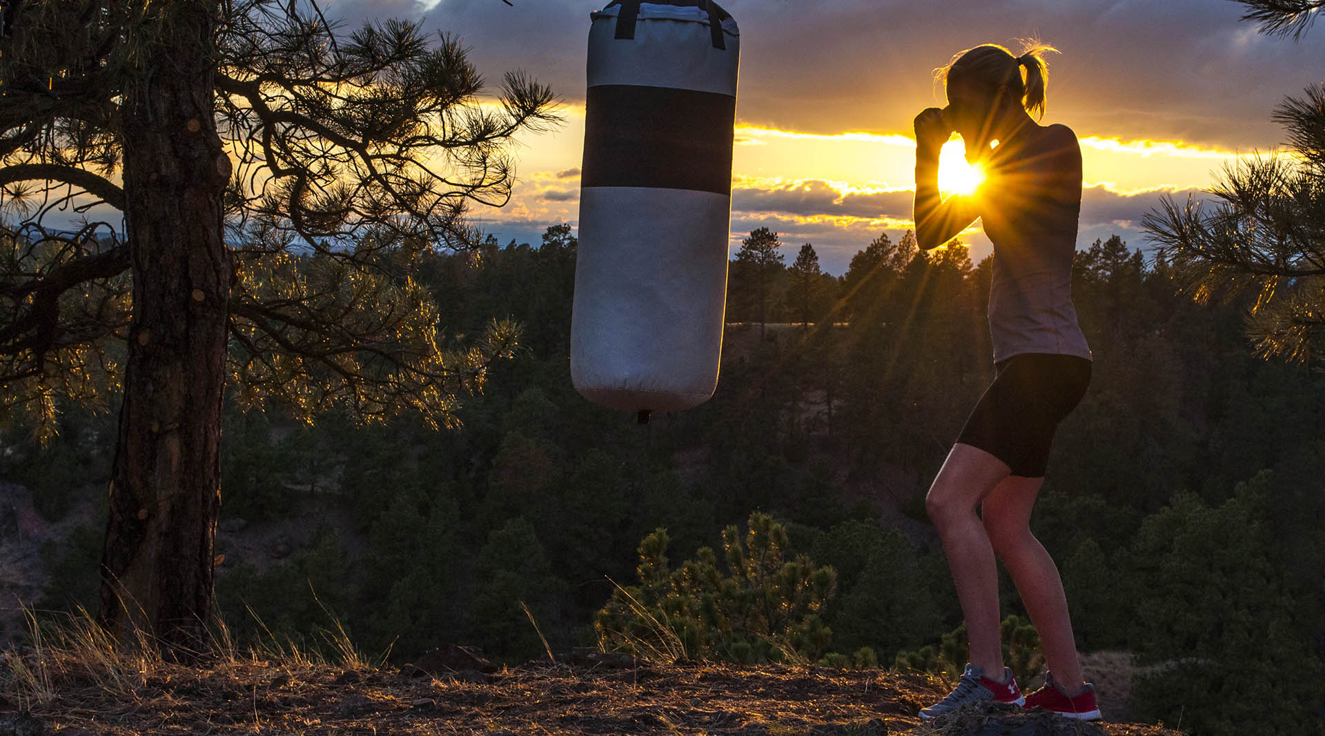 Katelyn Ely working a heavy bag at sunset atop a the majestic hills of Wyoming