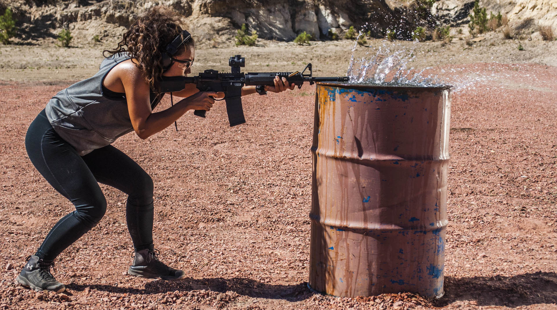 Steph discharges her AR across the top of a 55 gallon drum as the gasses from the barrel disrupt the surface water on top